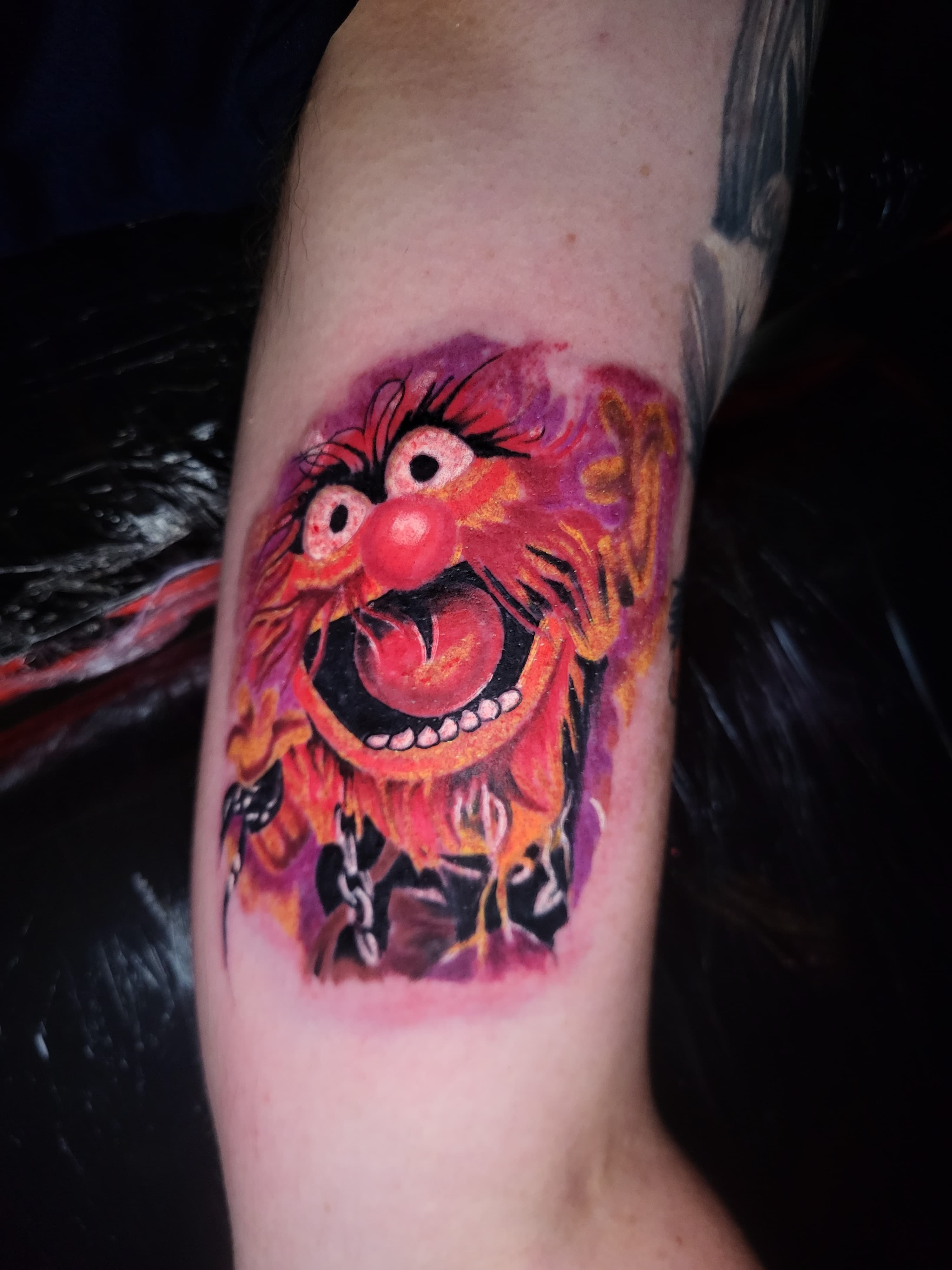 Kolorowy tatuaz Animala z Muppetów na ramieniu w stylu realistycznym z łańcuchami
