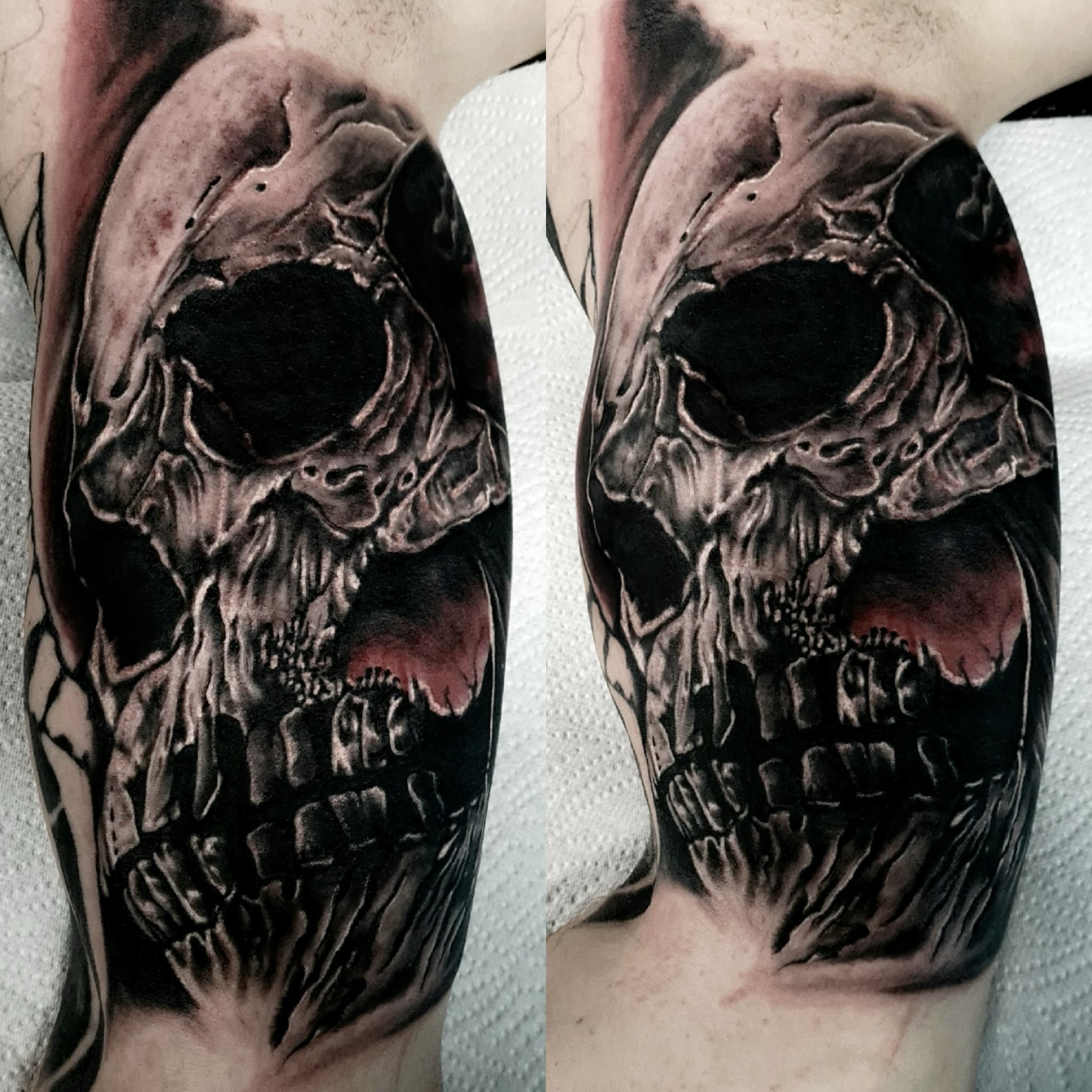Mroczny realistyczny tatuaz zniszczonej czaszki demona w czarno-szarej tonacji na ramieniu