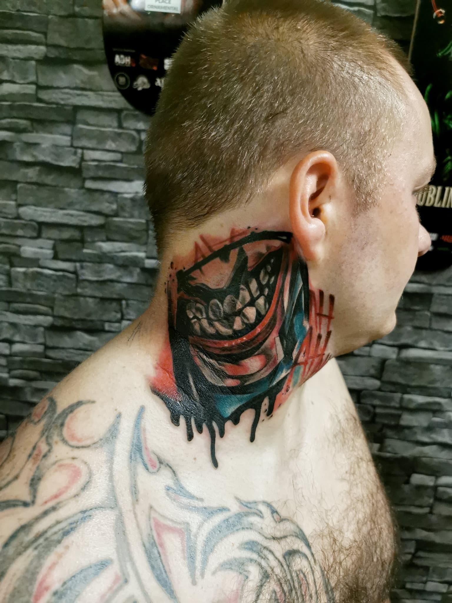 Kolorowy tatuaz demonicznego usmiechnietego pyska na szyi w stylu surrealistycznym