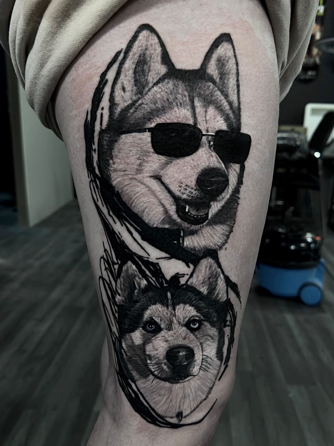 Tatuaż dwóch husky w stylu szkicowym z okularami przeciwsłonecznymi w odcieniach szarości na udzie