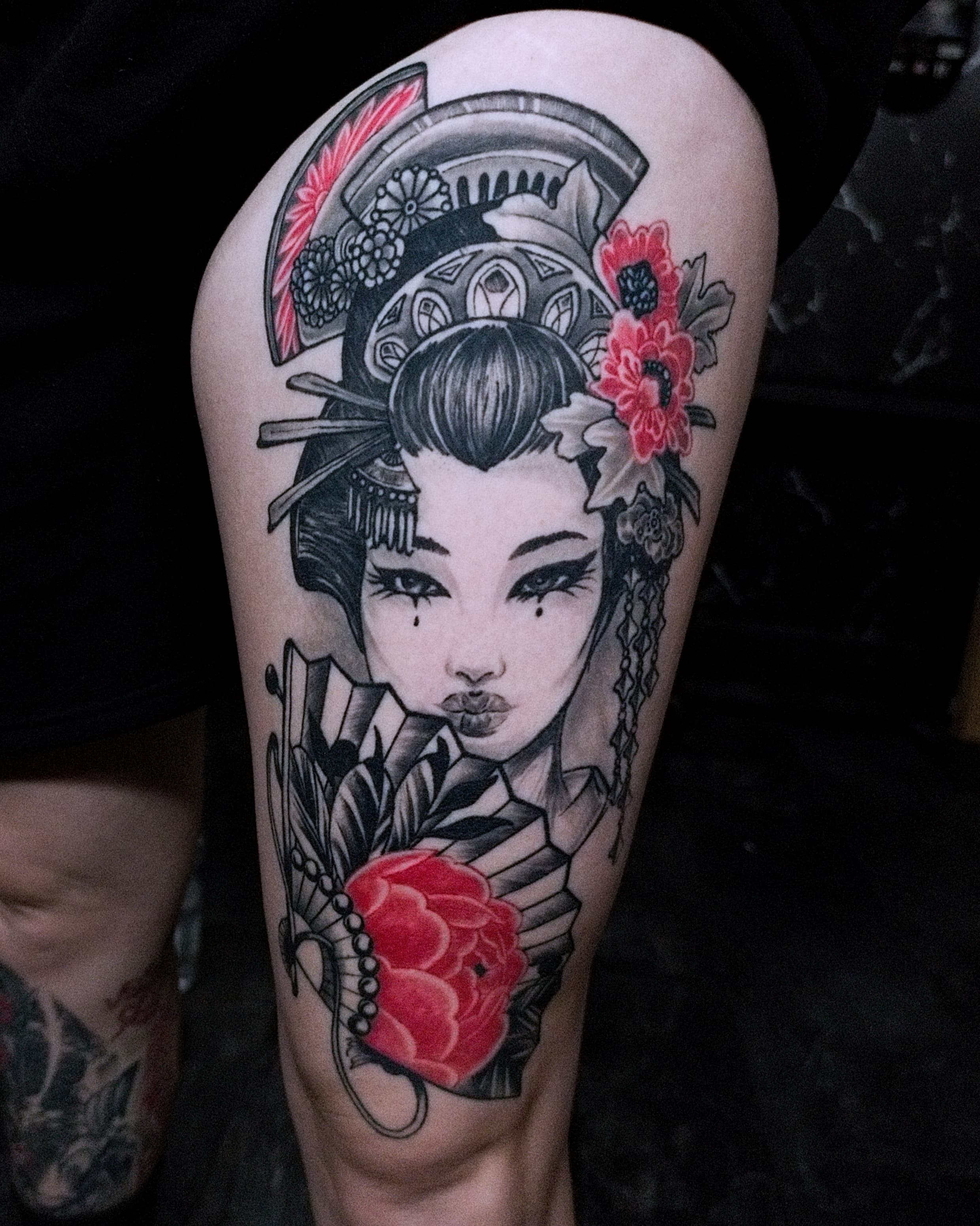 Czarno-bialy tatuaz gejszy japońskiej z wachlarzem i kwiatami na udzie w stylu neo-tradycyjnym