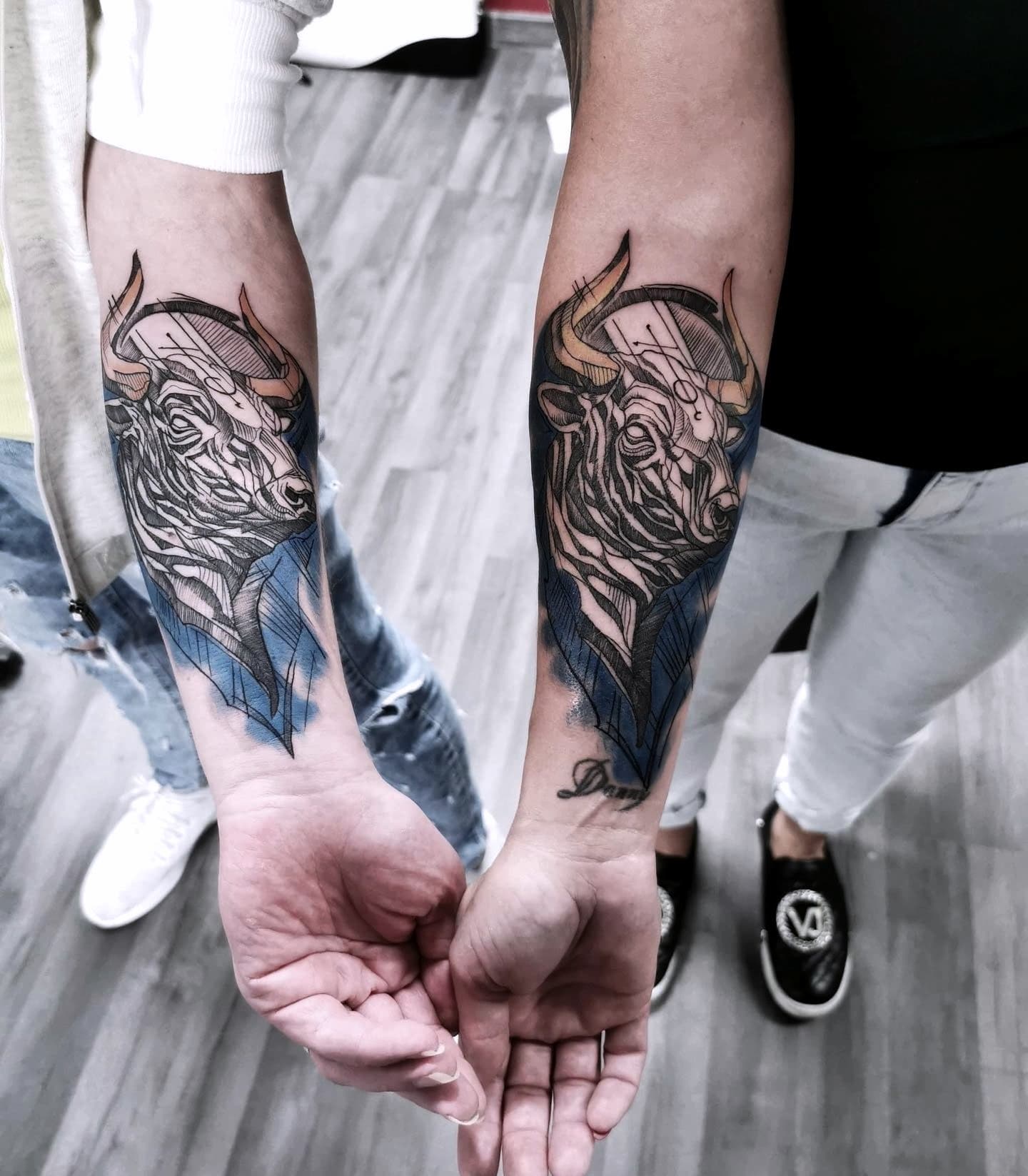 Parowane tatuaze zubrow w stylu geometrycznym na przedramionach dwoch osob