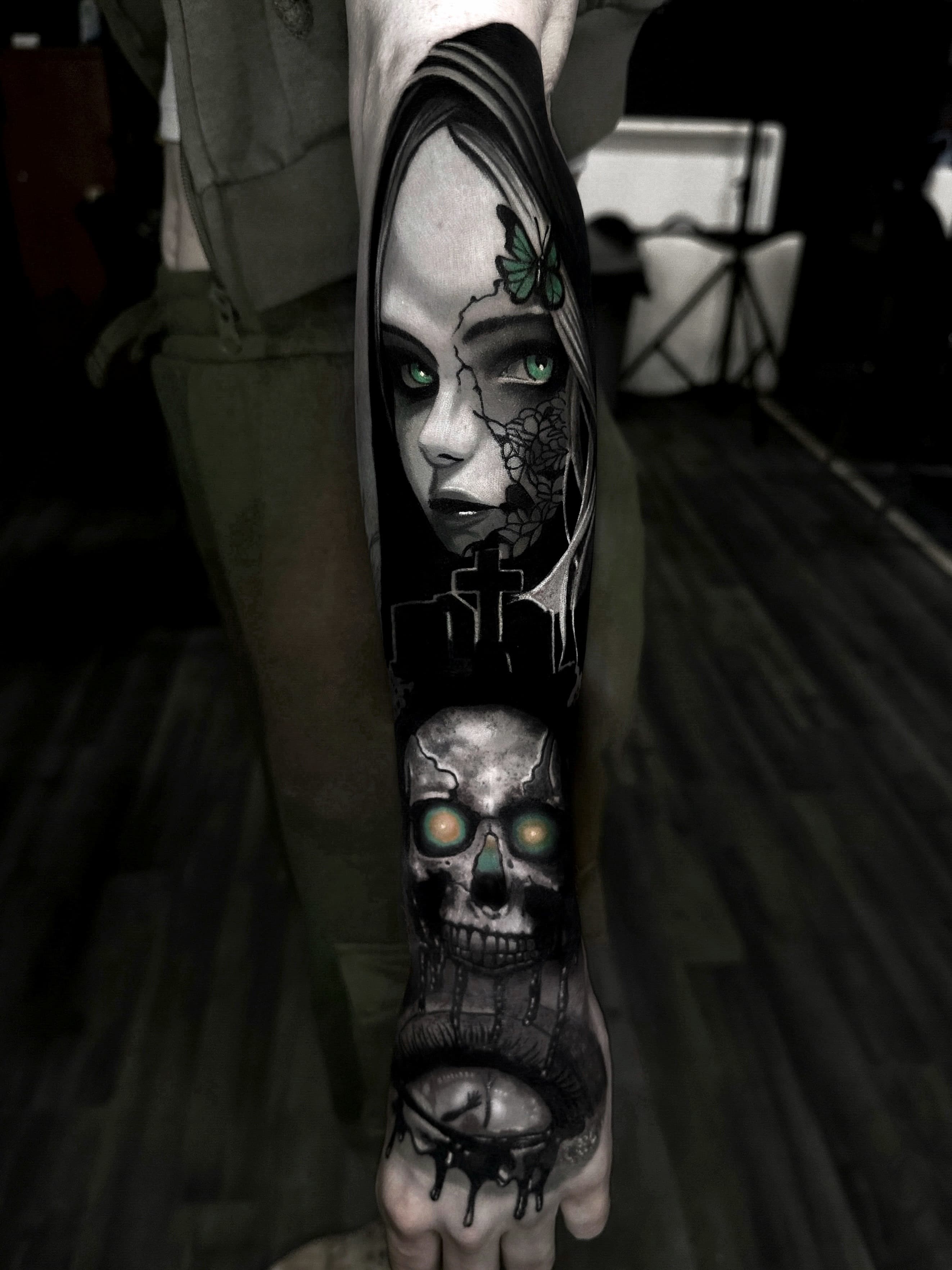 Mroczny tatuaz gotyckiej dziewczyny z motylem czaszka i krzyzem na przedramieniu w szaroscach