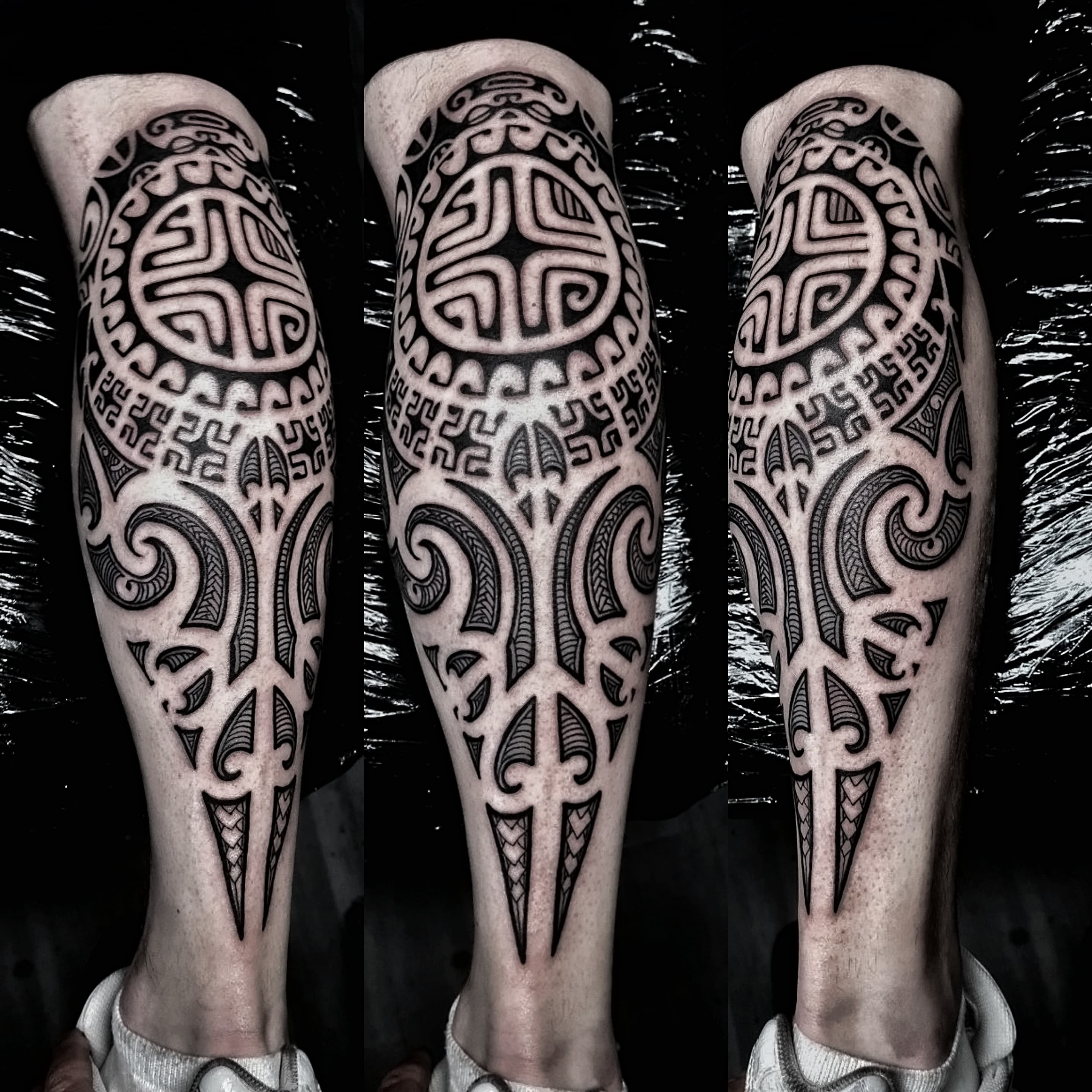 Czarno-bialy tatuaz w stylu maori na łydce z tradycyjnymi polinezyjskimi wzorami tribalnymi
