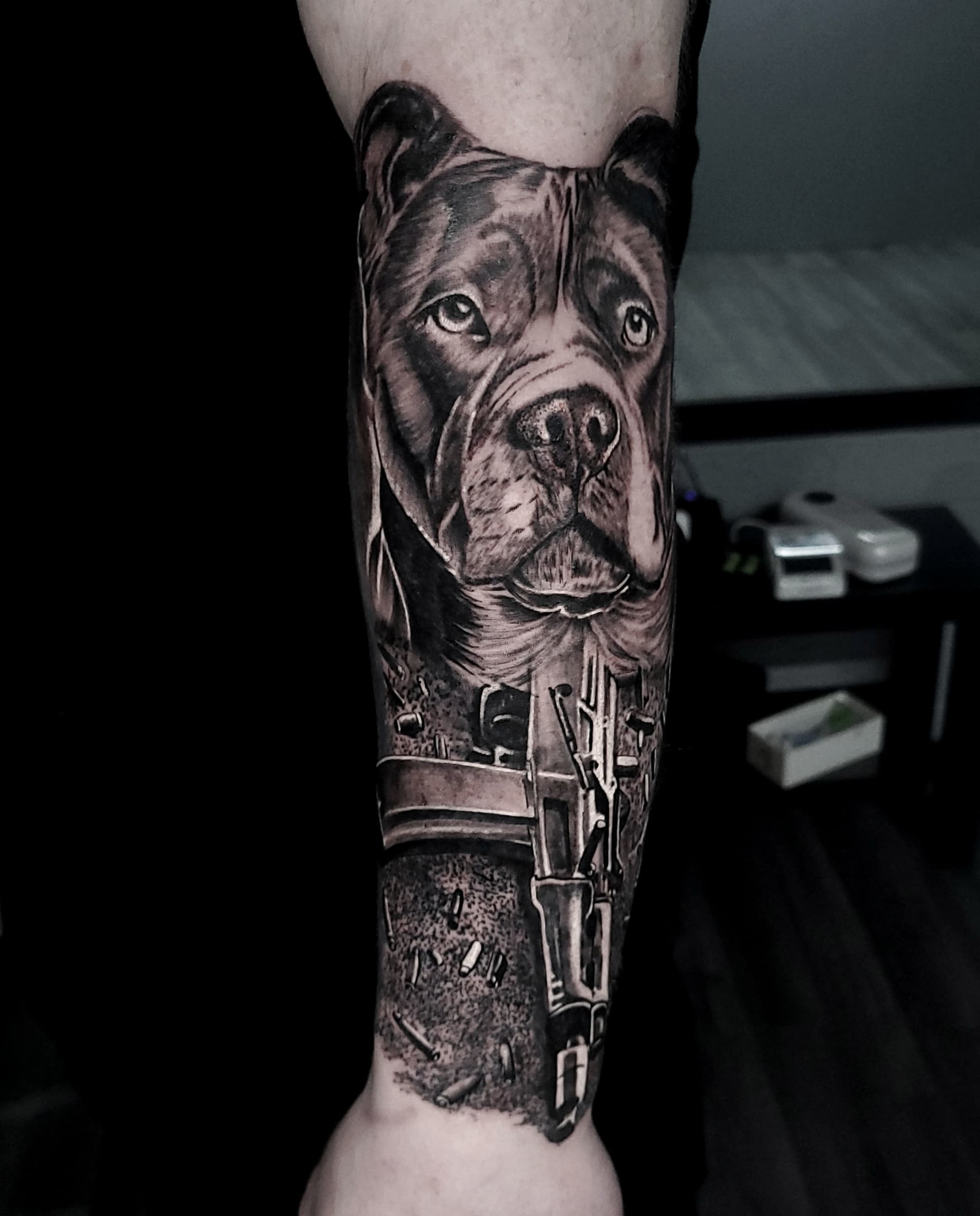 Realistyczny tatuaz portretowy psa pitbulla na przedramieniu w odcieniach szarości z krzyżami