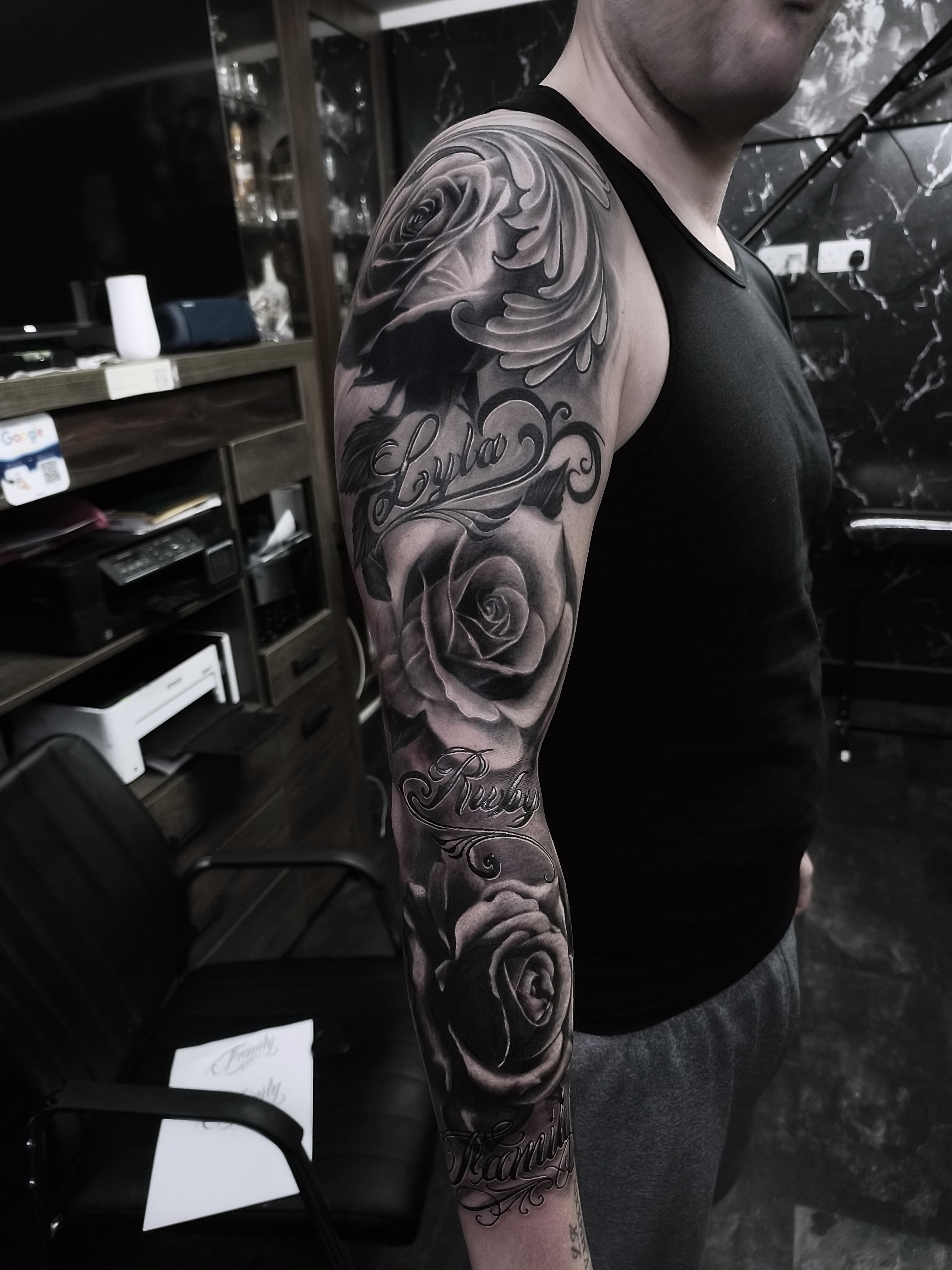 Czarno-szary rękaw tatuazu z trzema różami i ozdobnymi napisami imion w stylu chicano