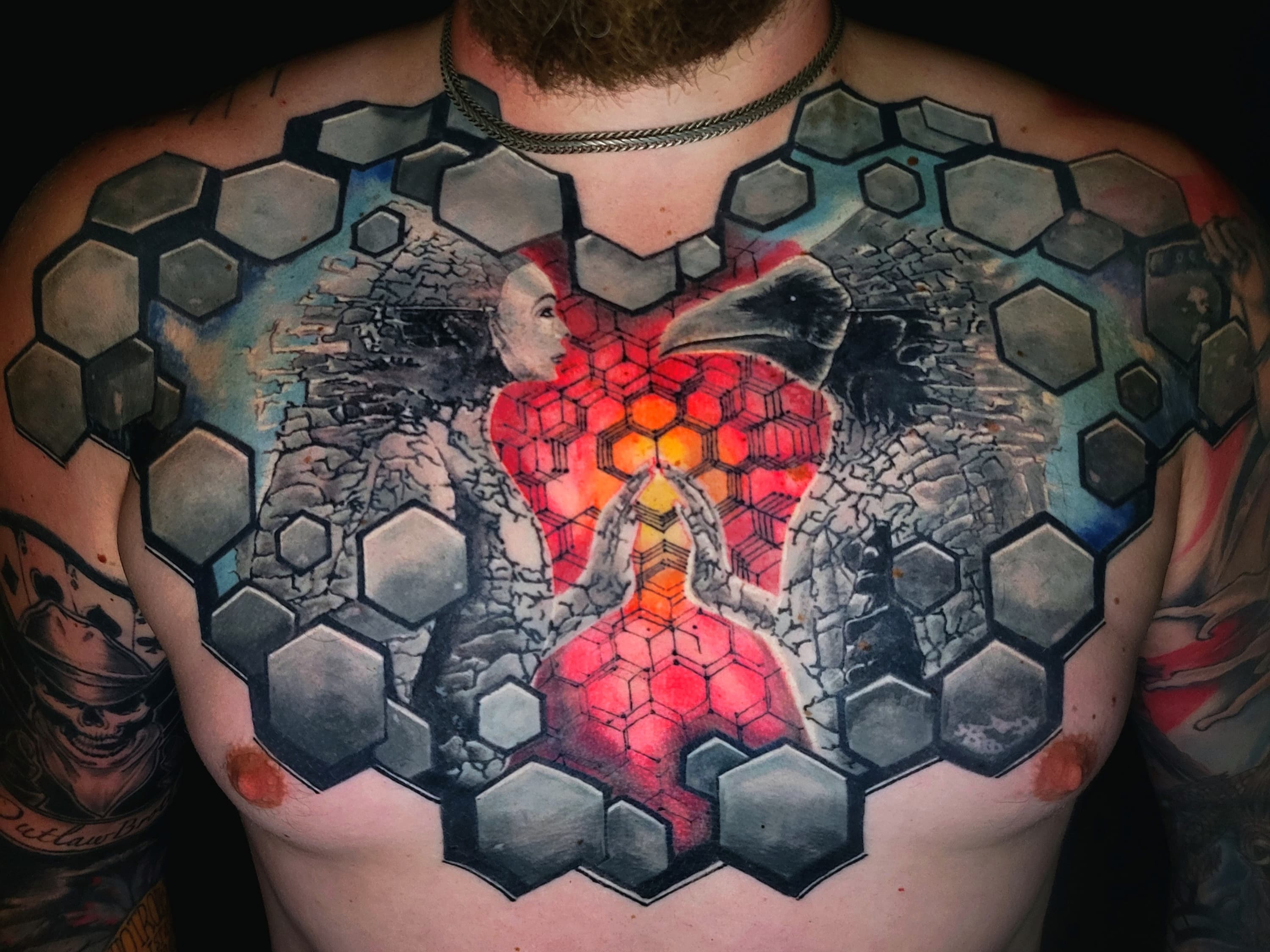 Surrealistyczny tatuaz na klatce piersiowej z heksagonami krukiem i modlącą się postacią
